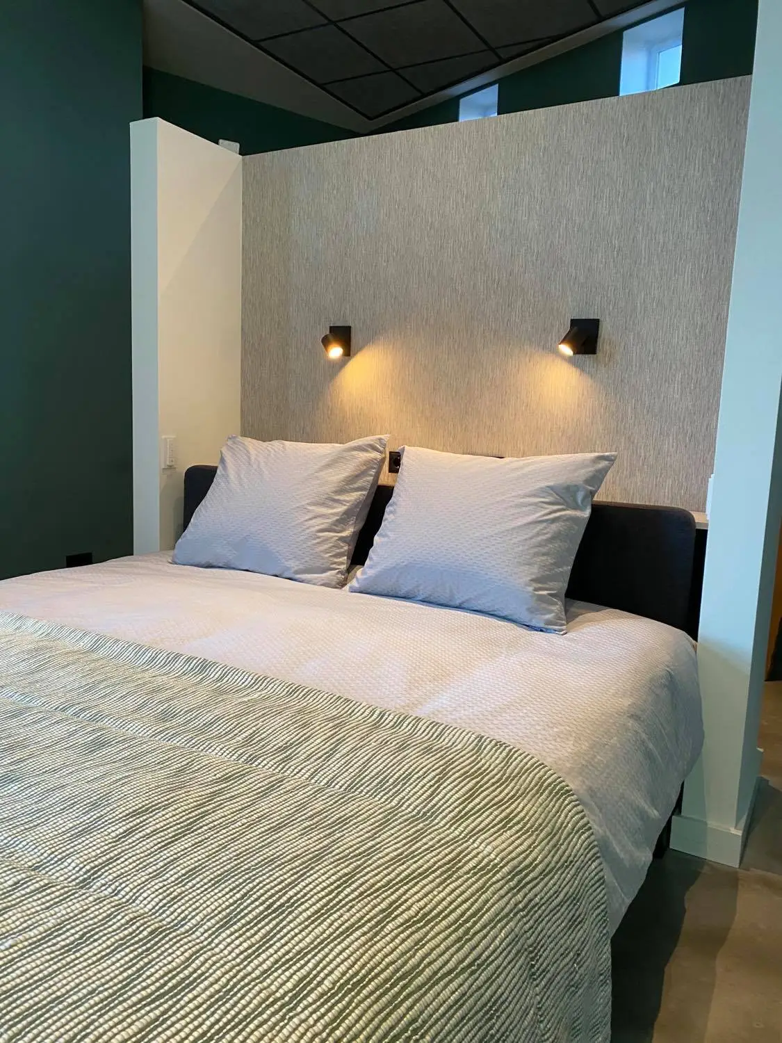 Das Bett in De Archivaris mit weißen Kissen und zwei Leselampen